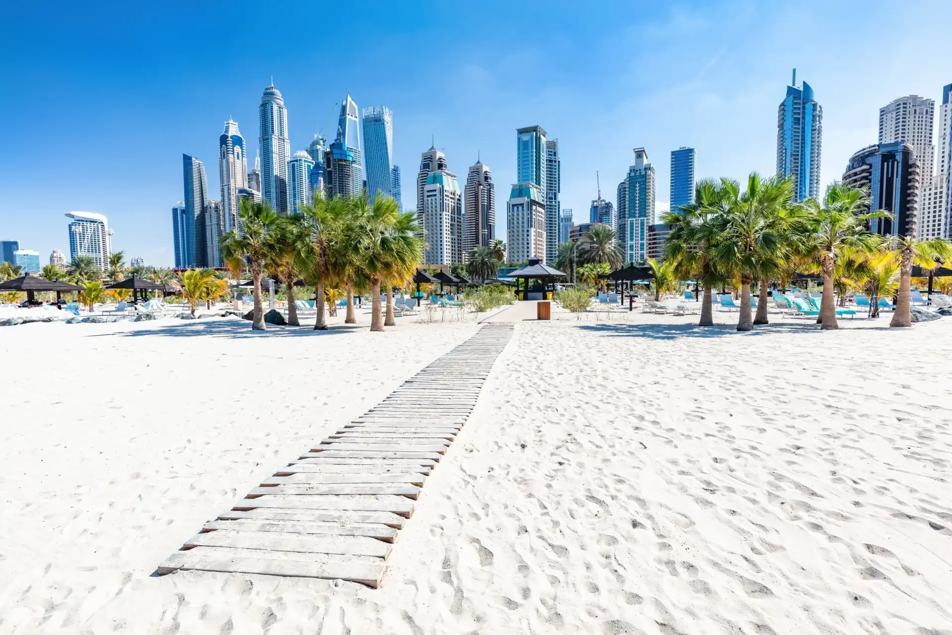 Jumeirah Beach Residence at Dubai Marina, featuring white sand, palm trees and impressive skyscrapers.