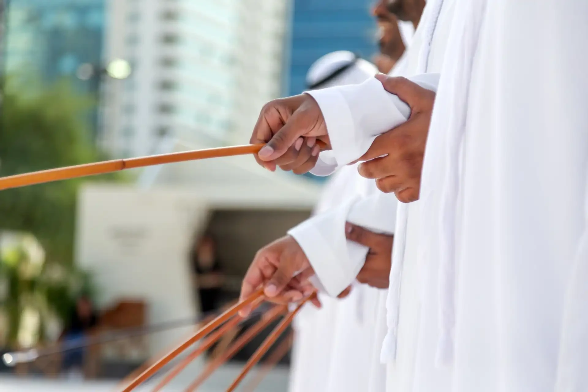 A close up of performers holding thin bamboo canes representing arrows or swords in as part of an Emirati dance.