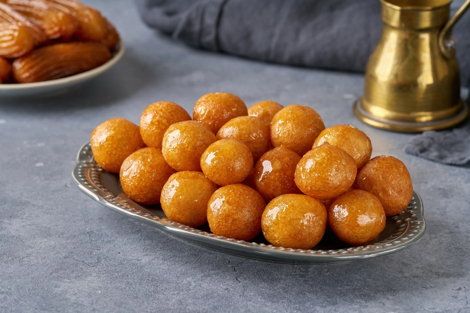 A plate of golden-fried spherical-shaped Luqaimat, a popular Emirati sweet treat.