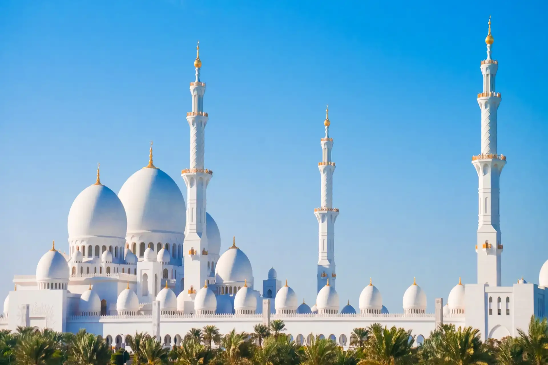 Sheikh Zayed Grand Mosque The Sheikh Zayed Grand Mosque against a clear blue sky, showcasing its stunning white marble architecture and intricate Islamic geometric patterns.