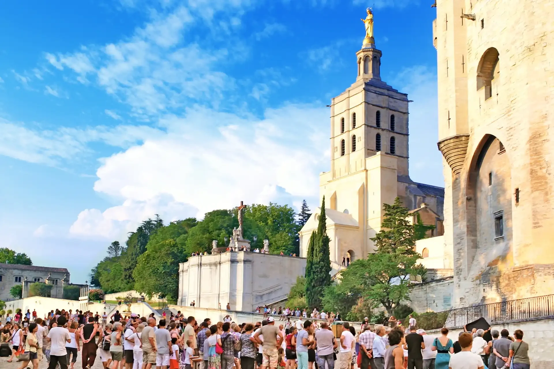 A line of people outside during the Festival d'Avignon, with a blue cloudy sky overhead.