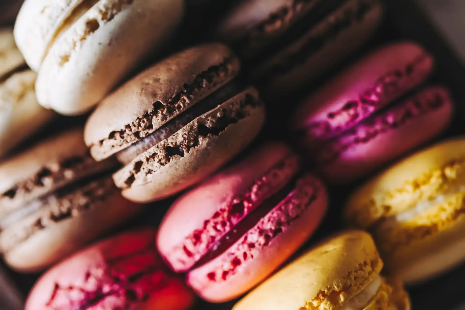 A close-up shot of brown, pink, and yellow macarons.