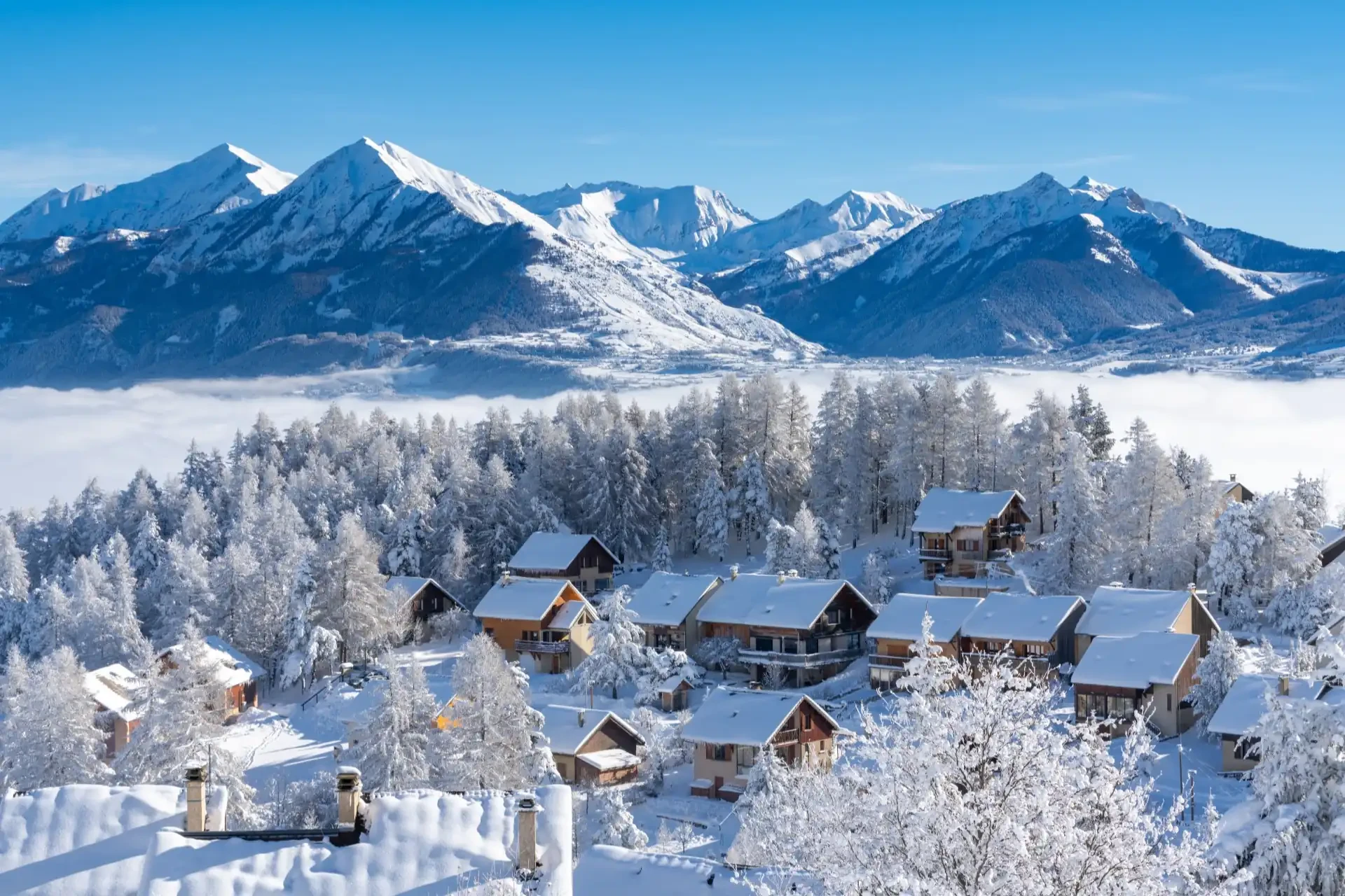 Fresh snow covers the roofs and trees of Laye winter ski resort in Champsaur, Hautes-Alpes, France.