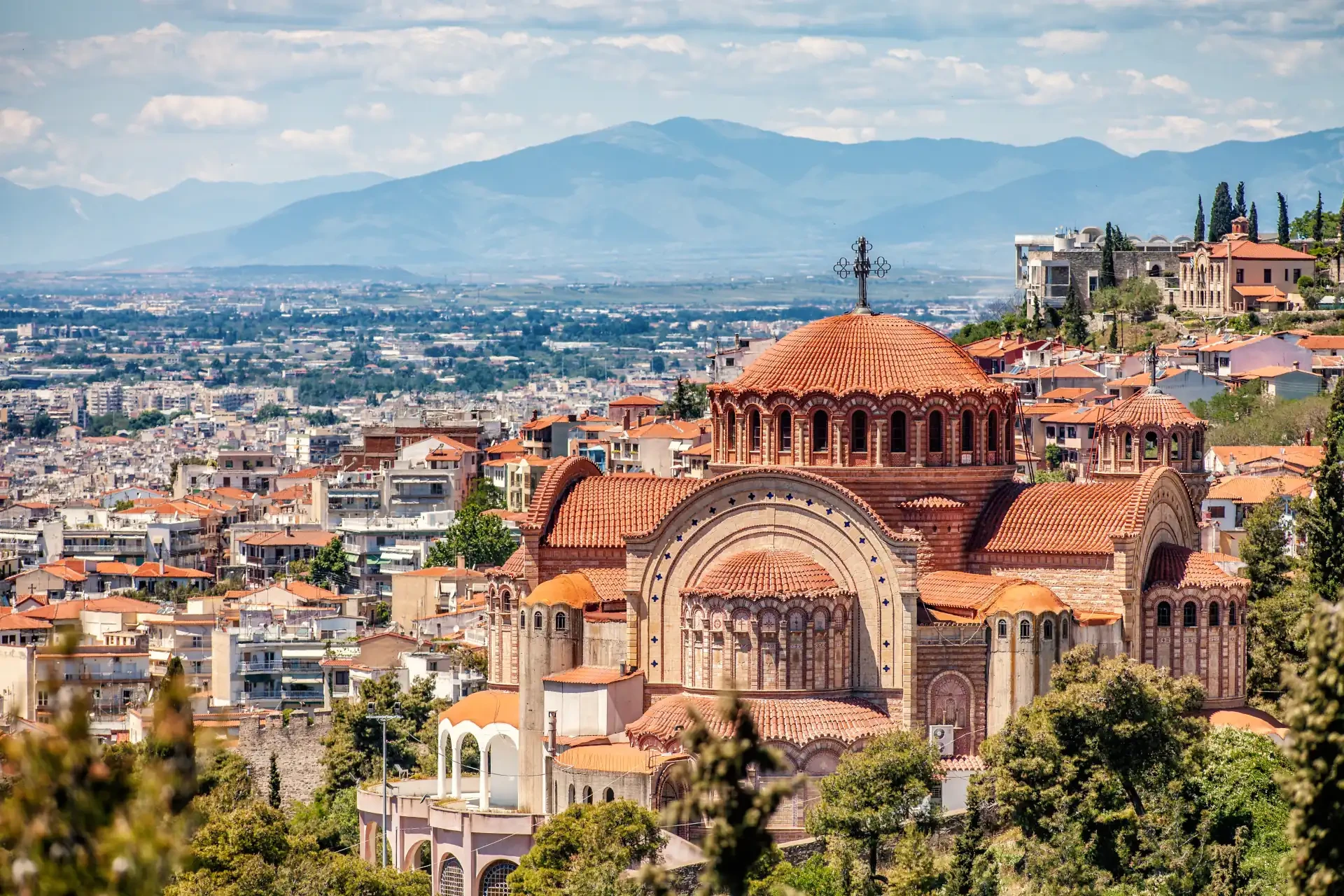 A panoramic view of Saint Paul Church in Thessaloniki city, Greece in front of a mountainous backdrop.