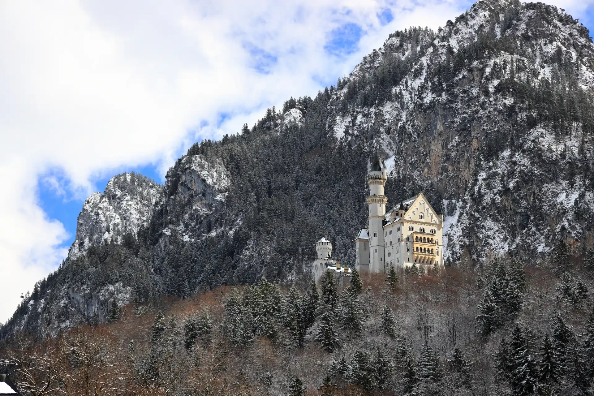 Neuschwanstein Castle set against the scenic backdrop of Bavaria, Germany. A cloudy sky surrounds the snowy scene.