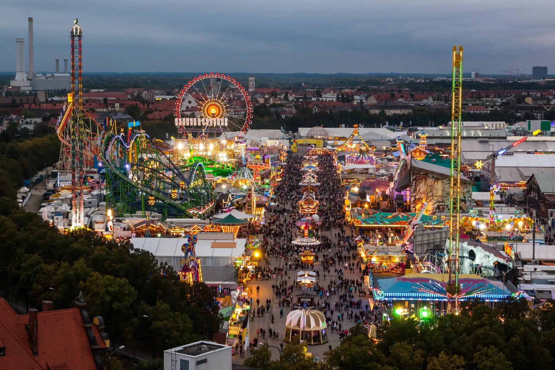 View of Oktoberfest in Munich at night, with vibrant lights, bustling crowds, and traditional beer tents.