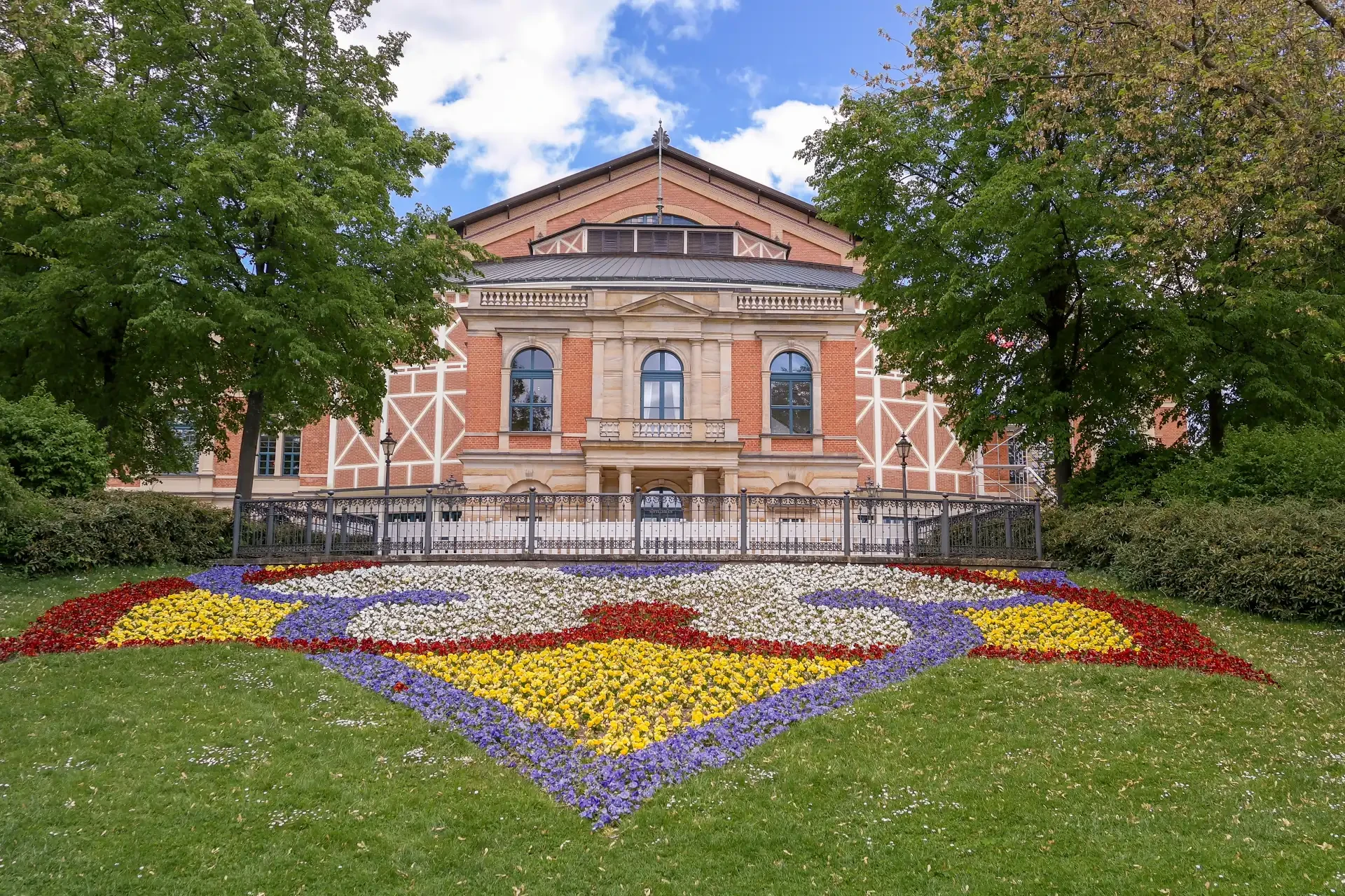 The Bayreuth Festival Hall in Germany, designed by Richard Wagner in the 19th century, known for its annual opera performances. Colourful flowers are planted at the front of the building.