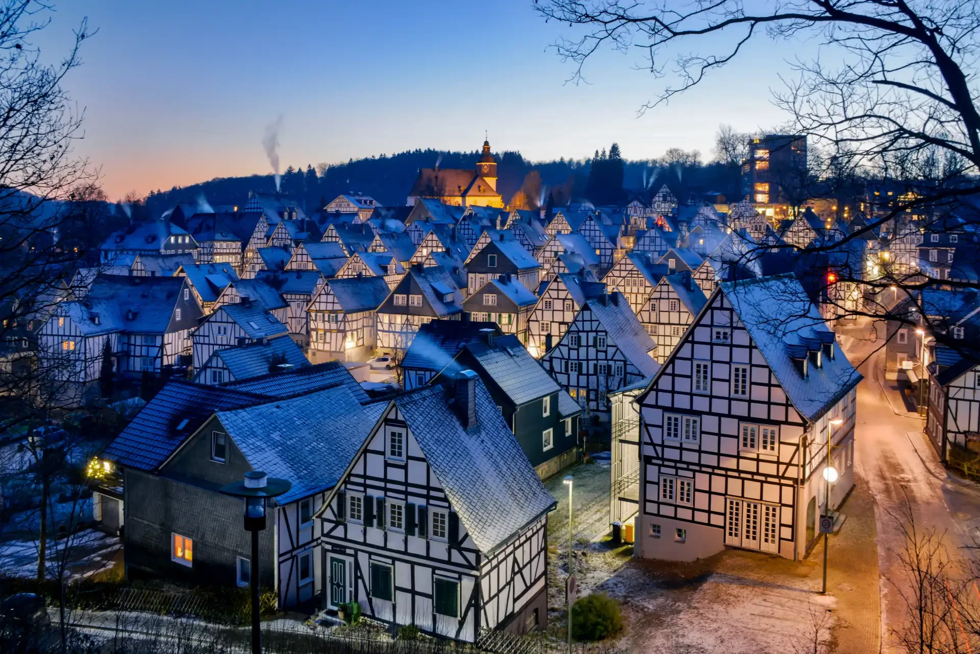 The winter landscape of Freudenberg Sauerland, Germany, with snow-covered rooftops and trees and traditional half-timbered houses.