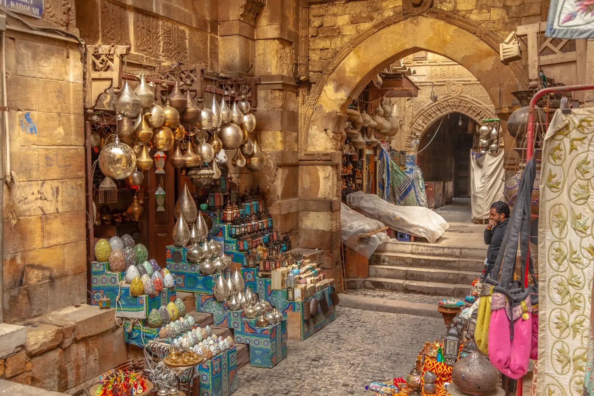 Archways in Khan El Khalili Bazaar, Cairo, with stalls displaying shiny and colorful trinkets for sale.