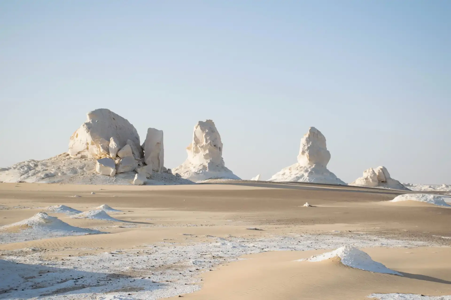 Otherworldly white rock formations against a pale blue sky.