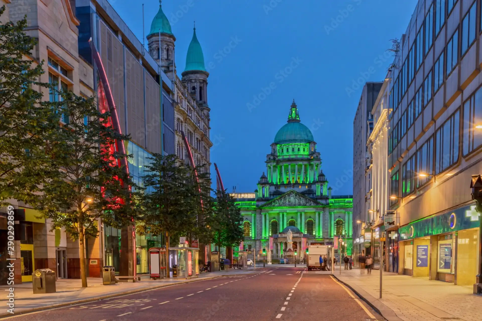 Belfast City Hall illuminated in vibrant green against a dark urban backdrop.