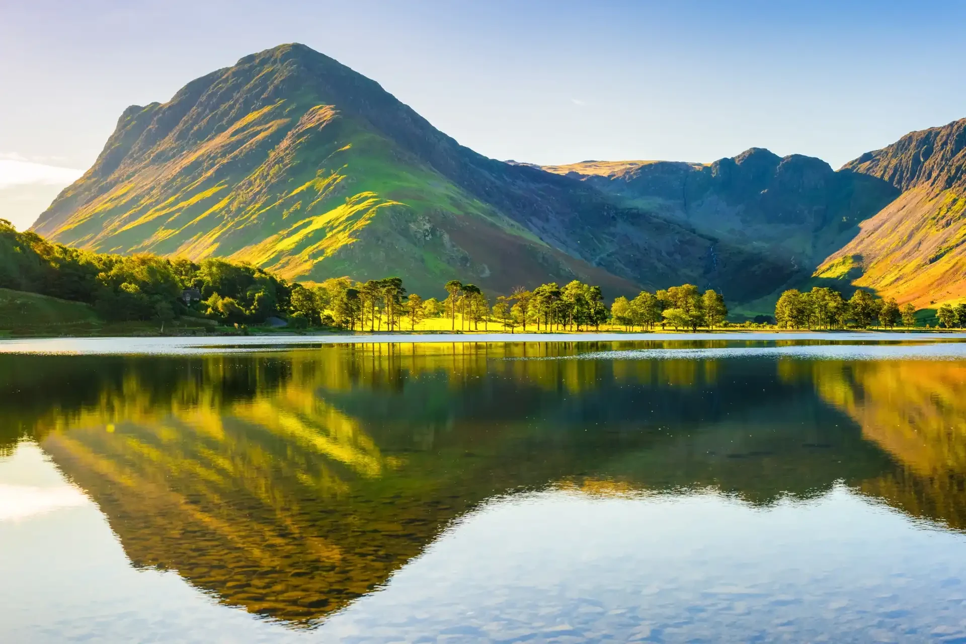 The picturesque Lake District landscape captures serene lakes surrounded by rolling hills and lush greenery.