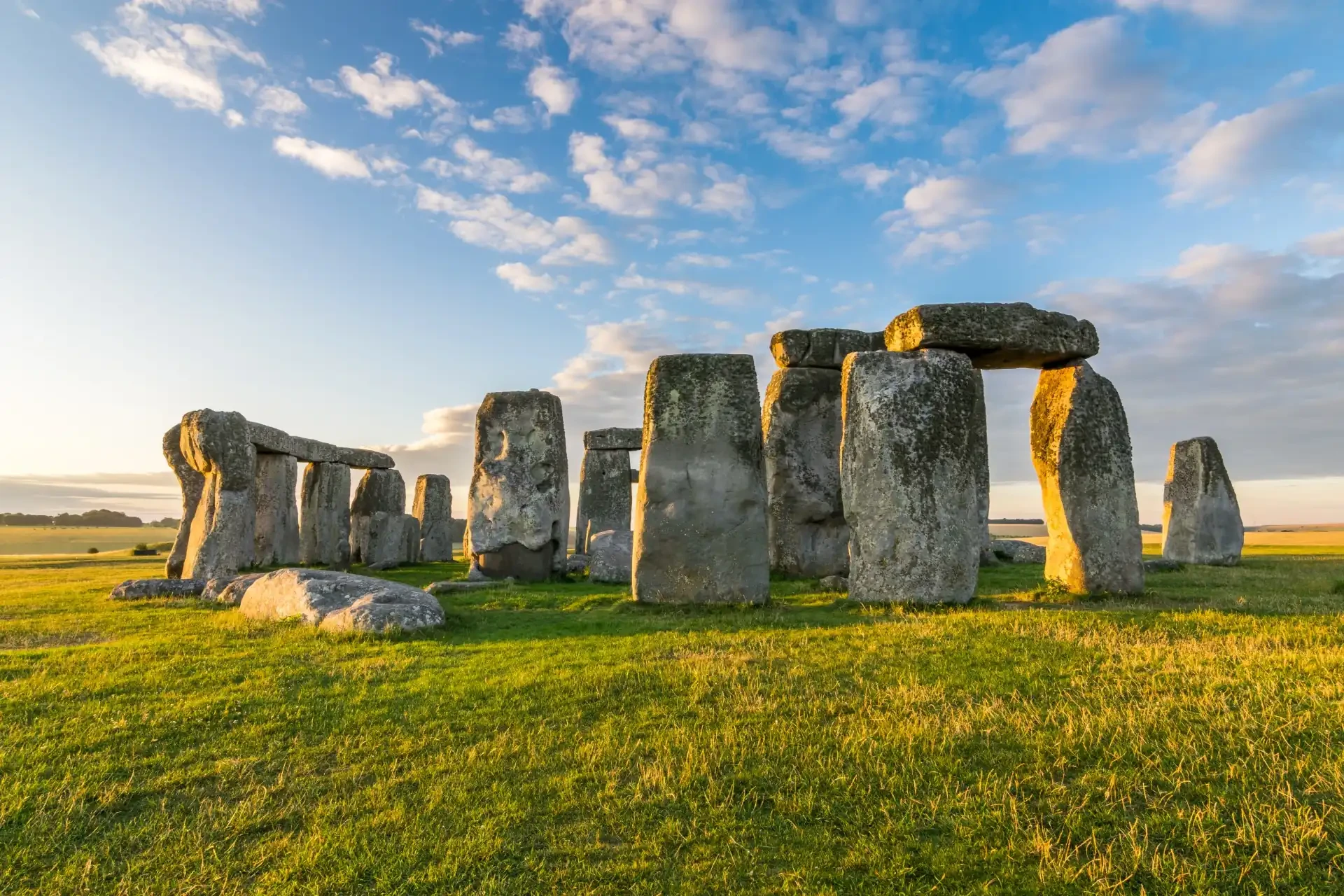 The iconic Stonehenge monument, featuring massive standing stones arranged in a circular pattern against a vast open cloudy sky.