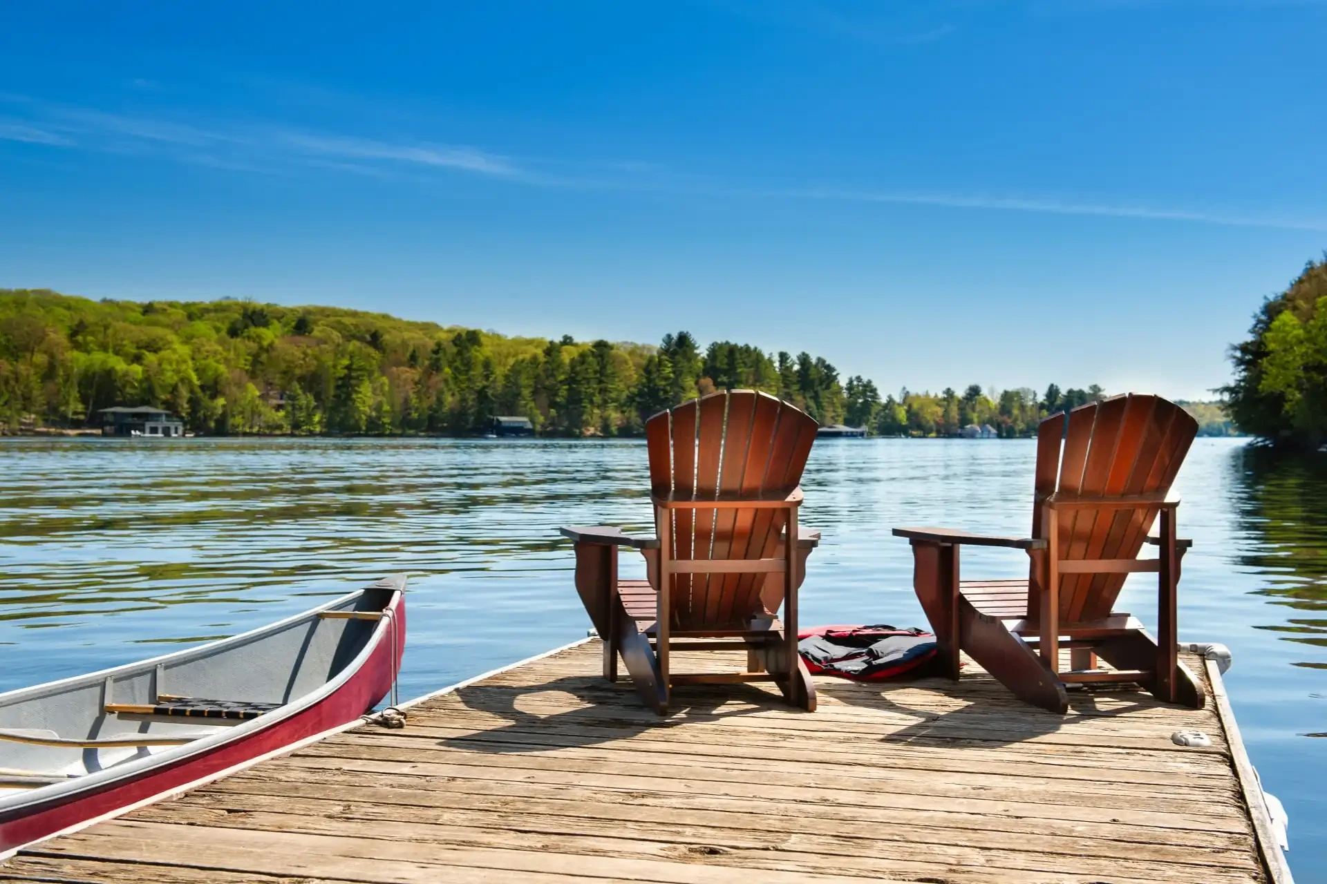 Adirondack chairs on a deck in Canada during summer, inviting relaxation and enjoyment of the warm weather.