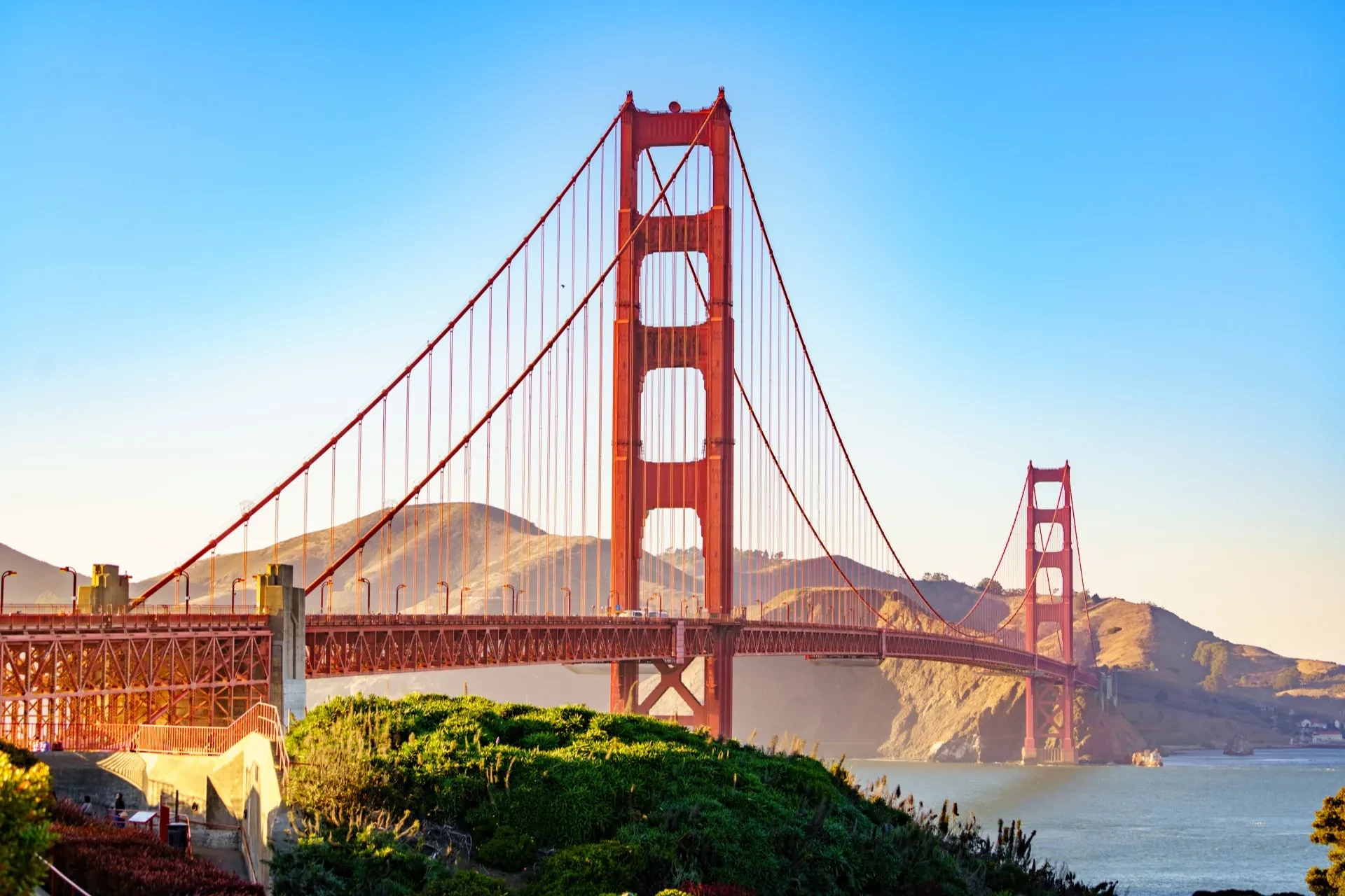 Golden Gate Bridge spanning across the San Francisco Bay, with its distinctive orange color emphasised against a blue sky backdrop.