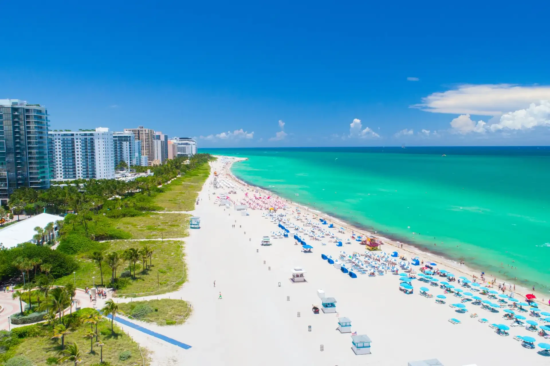 An aerial view of Miami Beach with white sand, blue ocean, and rows of deckchairs.