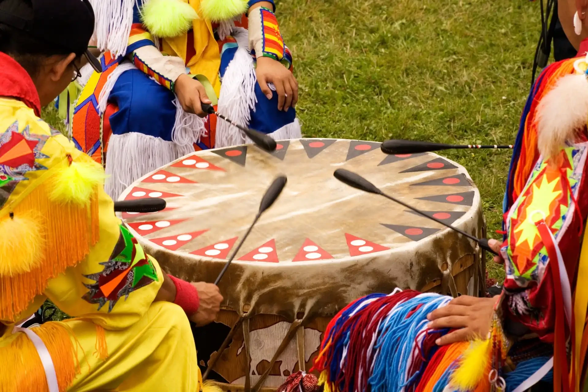 A captivating scene of people seated in a drumming circle, adorned in traditional regalia at a Native American Powwow.
