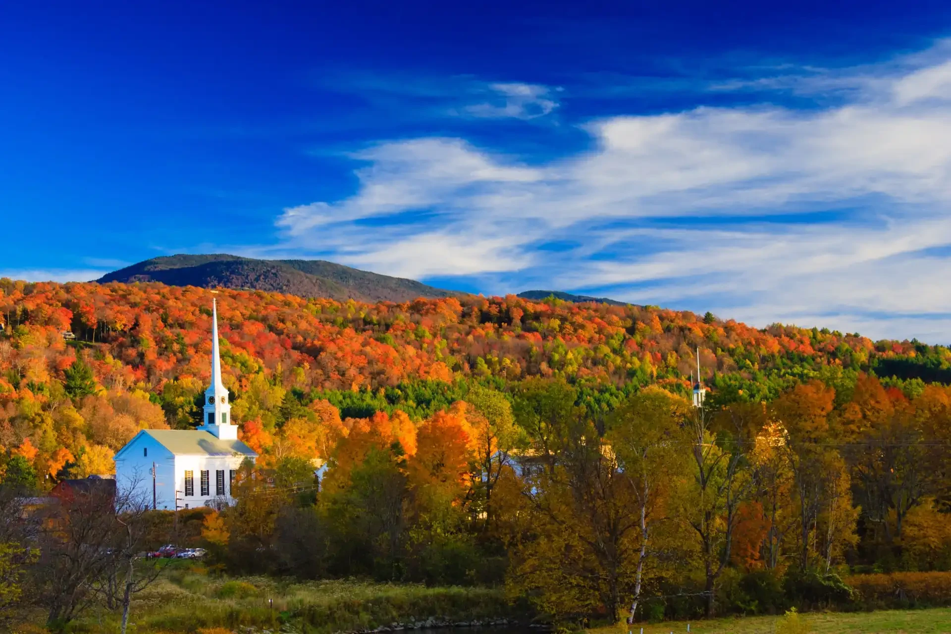 An autumn landscape in rural Vermont with a traditional church and vibrant fall foliage.