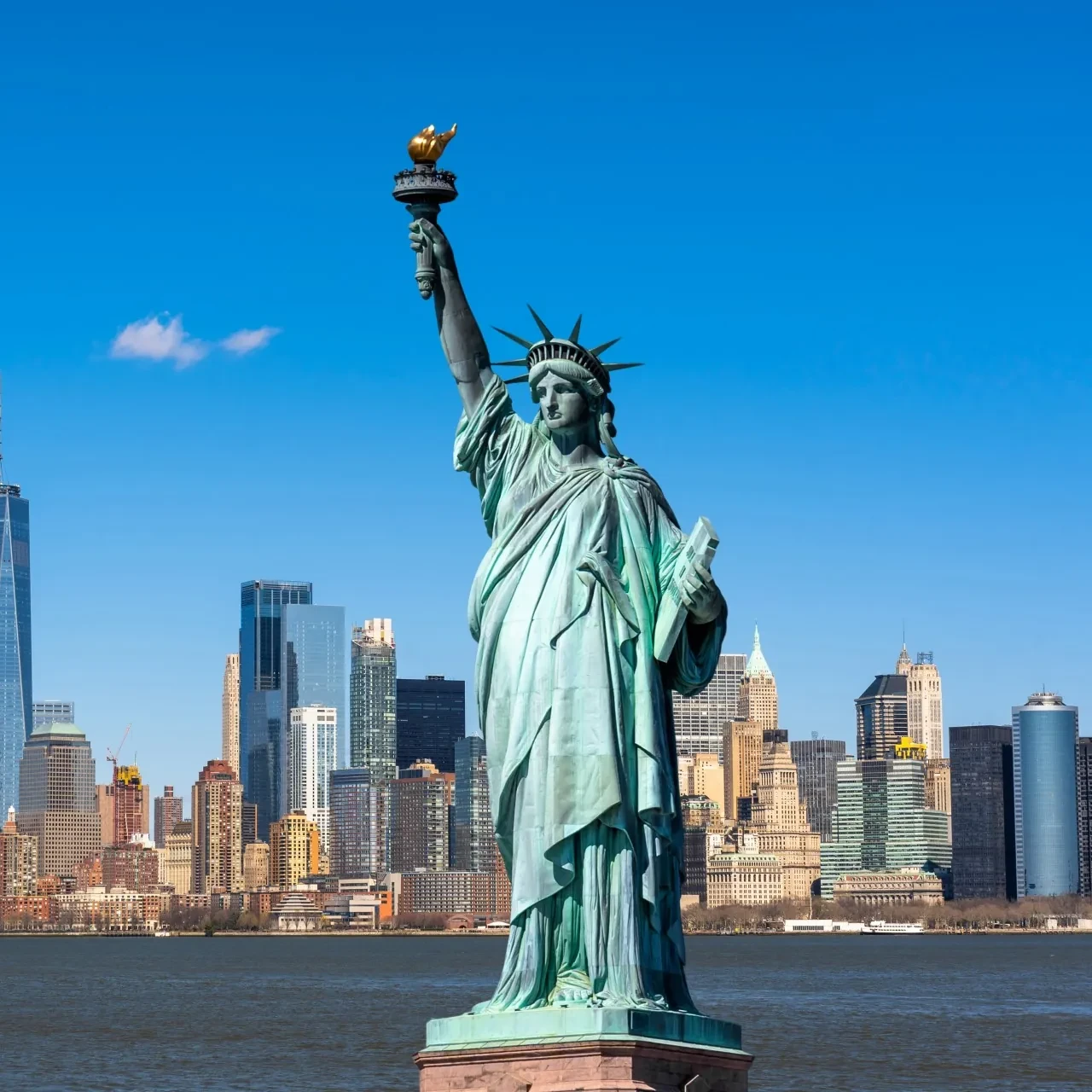 The Statue of Liberty against a clear blue sky, symbolising freedom and democracy in New York Harbour.”