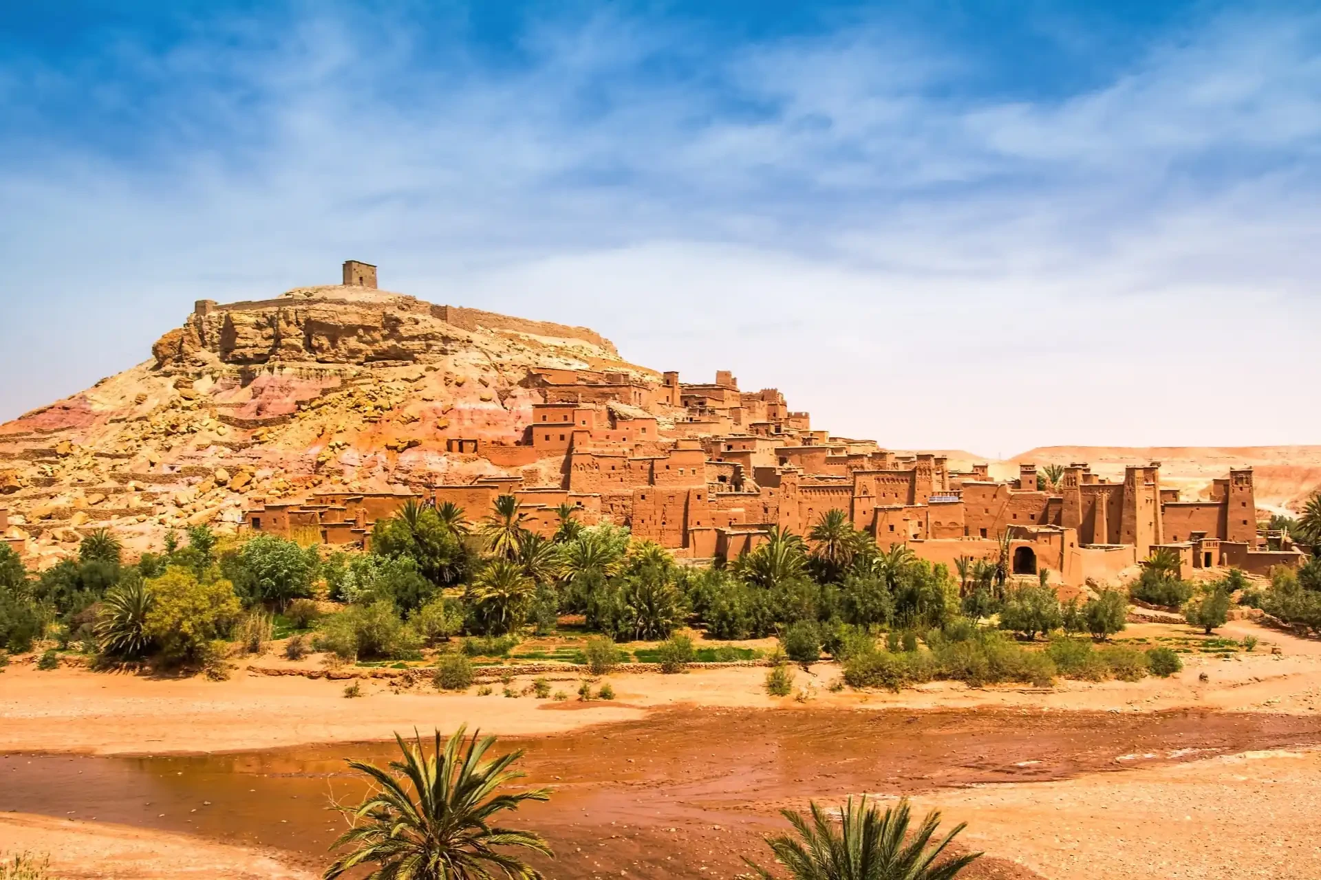 Ancient sand-coloured Moroccan fortress against the backdrop of a desert landscape.