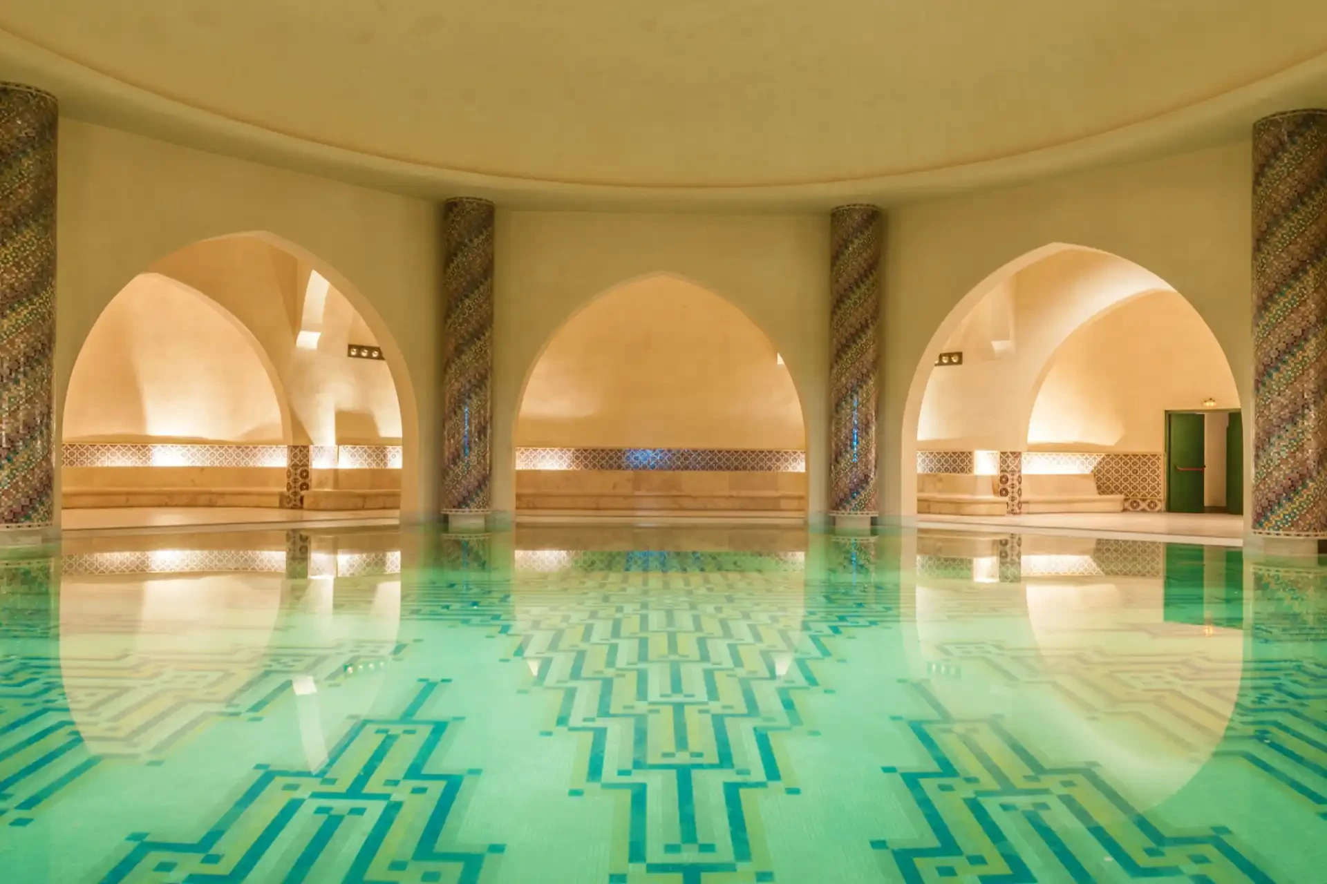 Interior of a traditional Moroccan hammam with warm lighting and mosaic tiles.