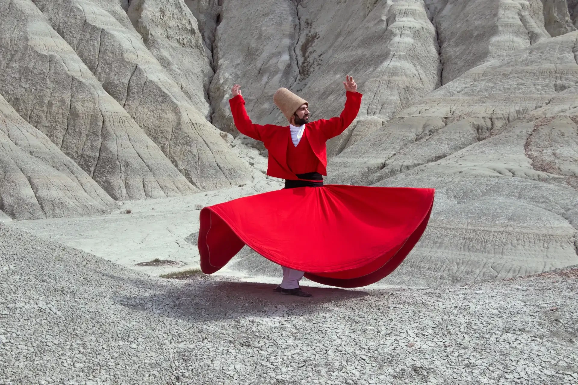 A man in traditional red costume carrying out a Whirling Dervish performance, a traditional Sufi dance."